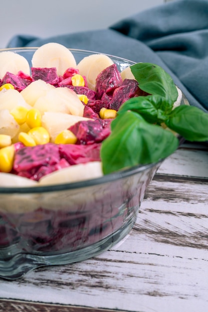 Bietenananas mais palmharten en witlofsalade met olijfolie en basilicum in een glazen kom