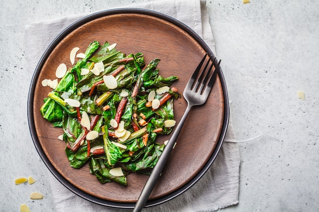 Bietengreens salade met noten in zwarte plaat, gezond veganistisch voedselconcept.