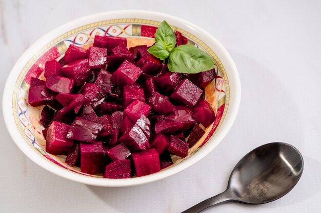 Bietensalade met olijfolie en basilicum in een bord op een witte marmeren achtergrond