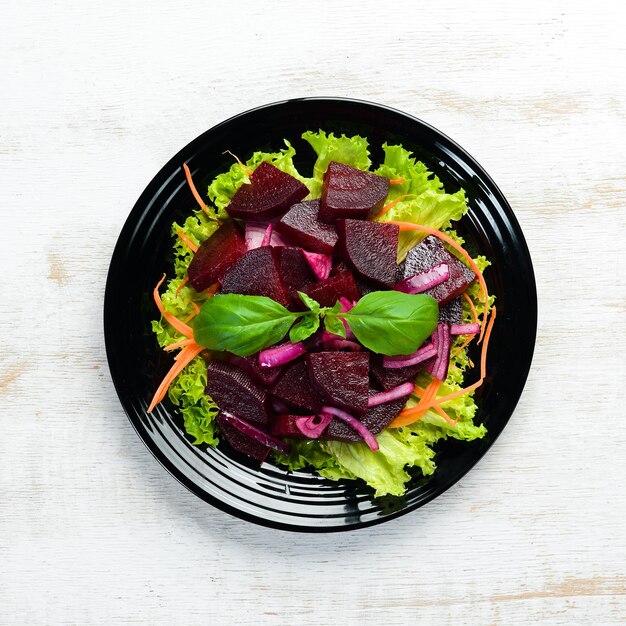 Bietensalade met uien in een zwarte plaat op een witte houten achtergrond Bovenaanzicht Vrije ruimte voor uw tekst