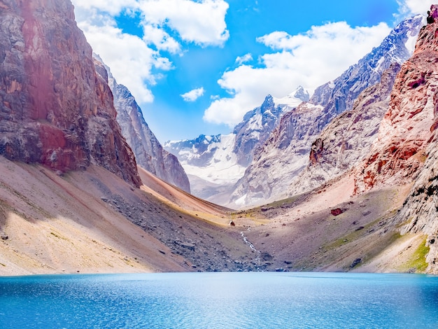 바위 산 배경에 햇빛에 청록색 물과 큰 알로 산 호수. Fann Mountains, 타지키스탄, 중앙 아시아