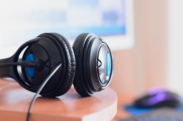 Big black headphones lie on the wooden desktop of the sound 