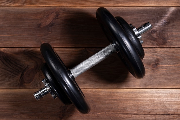 Big black male dumbbell on a brown wooden table