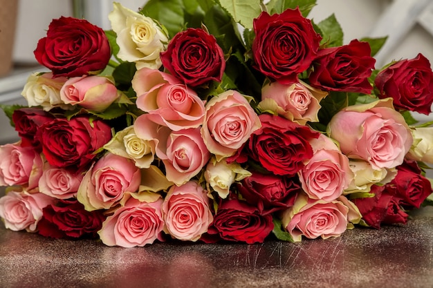 Big bouquet of multicolored roses, on table