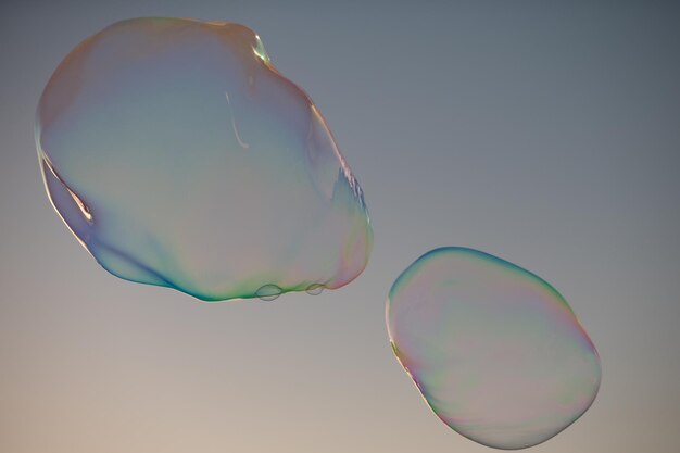 青い空の上を飛んでいる大きな泡巨大なカラフルなシャボン玉が曇り空の背景の上を飛んでいます