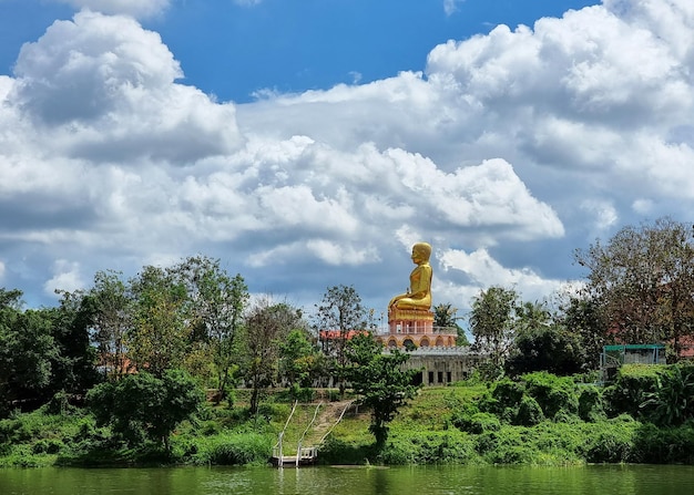 Big Buddha image on clouds in the blue sky background at Wat Chom Prasat Ratchaburi Thailand