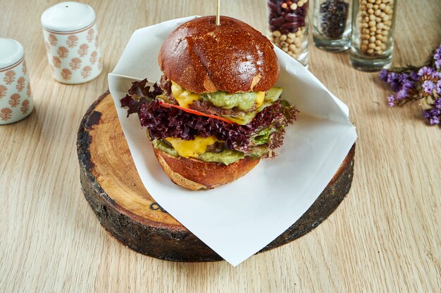 Big burger with meat, cheese, onions, guacamole on a wooden table. Tasty street food. view