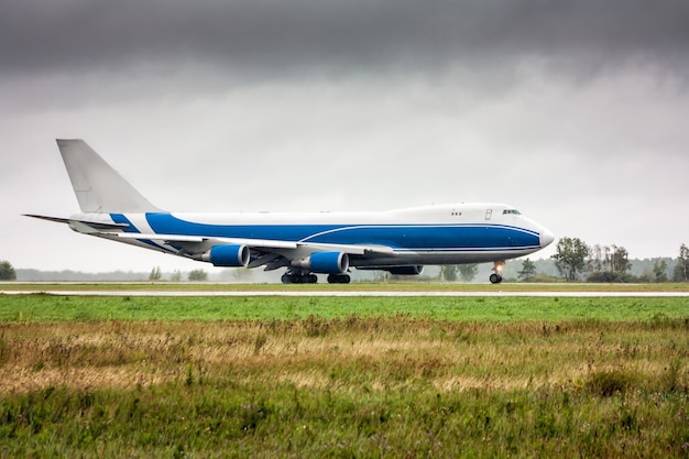 Big cargo airplane moves on the main taxiway in heavy rain