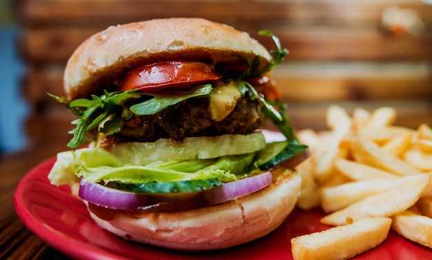 Big cheeseburger and chips on a plate.