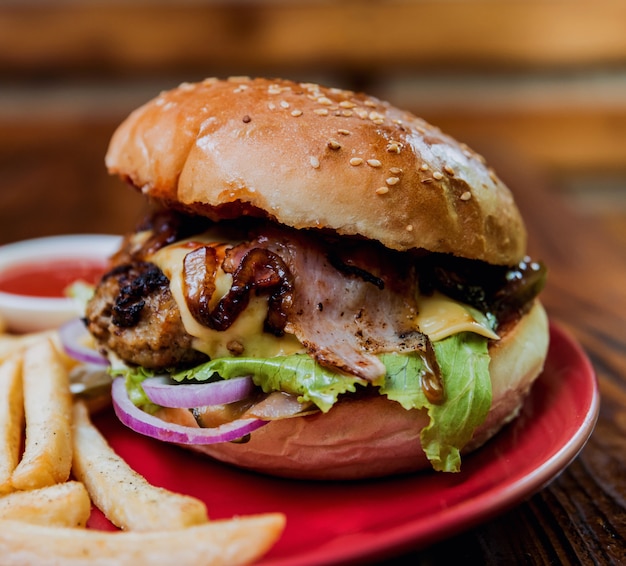 Big cheeseburger and chips on a plate.