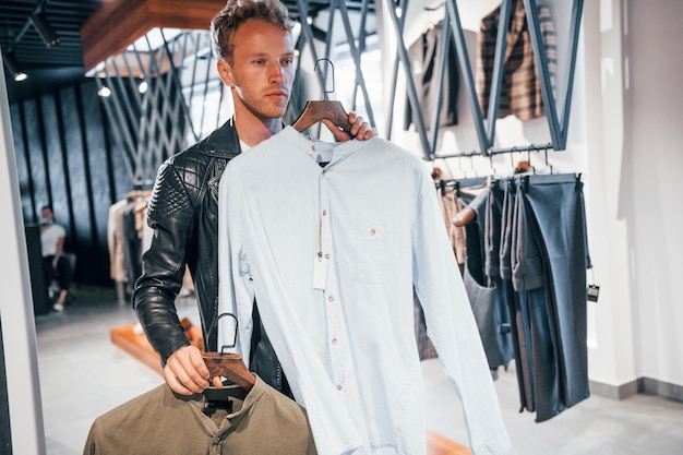 Photo big choice young guy in modern store with new clothes elegant expensive wear for men