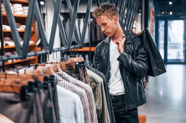 Big choice Young guy in modern store with new clothes Elegant expensive wear for men