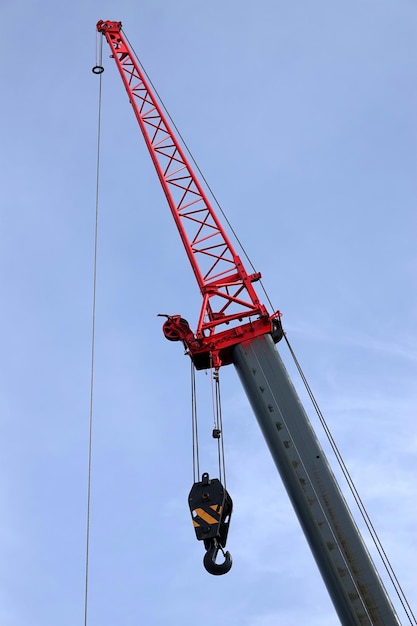 Big construction arm crane with heavy hook on clear blue sky closeup view vertical photo