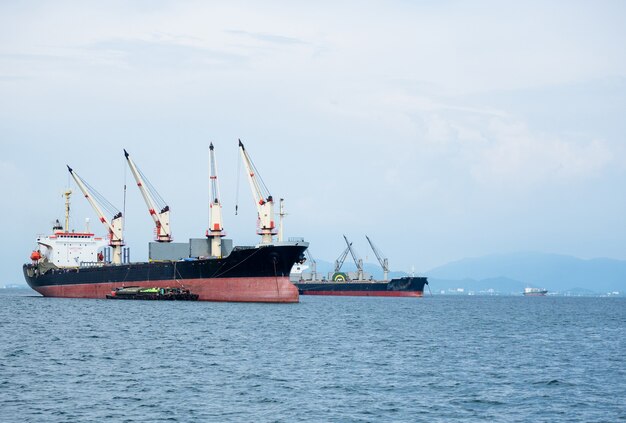 사진 바다와 섬 배경의 산에 있는 산업 선박의 큰 크레인