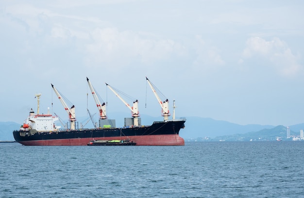 Big crane in the industrial ship in the ocean and mountain in island background