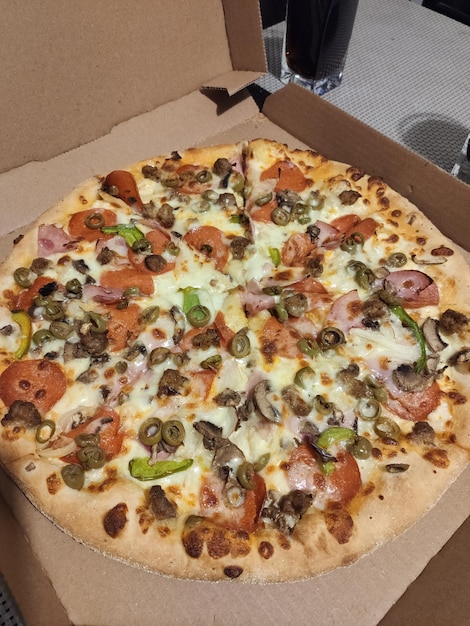 A big delivery pizza in a box with olives and sausages