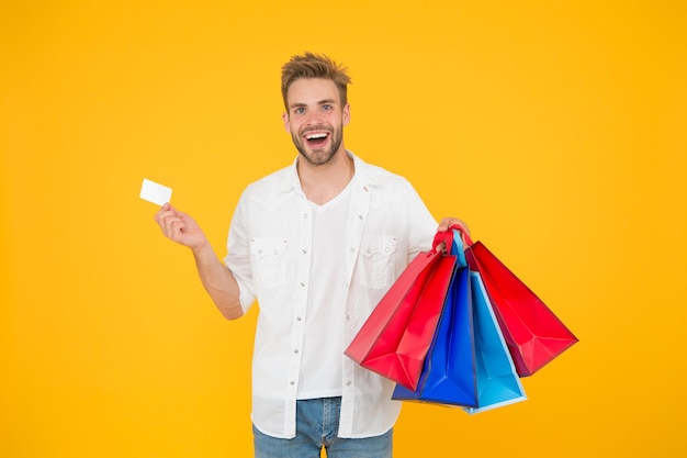 Grande sconto. ottime scelte ottimi acquisti. uomo felice che tiene gli acquisti in sacchetti di carta. consumatore cliente cliente allegro sorridente con acquisti di moda. acquisti d'impulso. il concetto di consumismo.