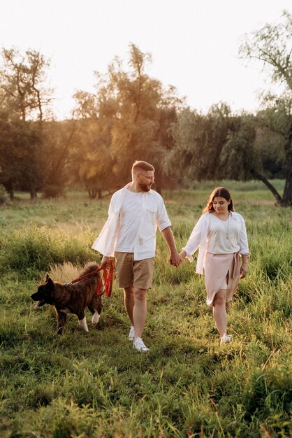 Big dog for a walk with a guy and a girl on the green prairie