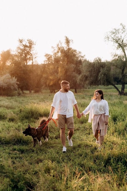 Big dog for a walk with a guy and a girl on the green prairie