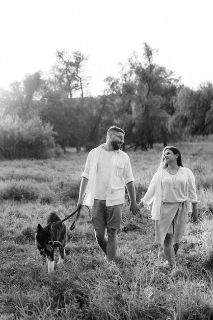 Photo big dog for a walk with a guy and a girl on the green prairie