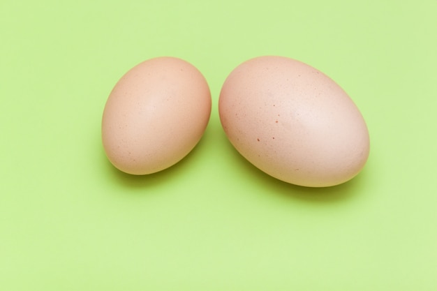 A big egg and a small egg on the light green background.