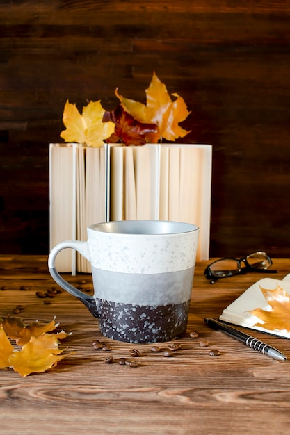 Big espresso coffee cup tea mug with booksnotebookon tablehot beverage in autumn cozy evening