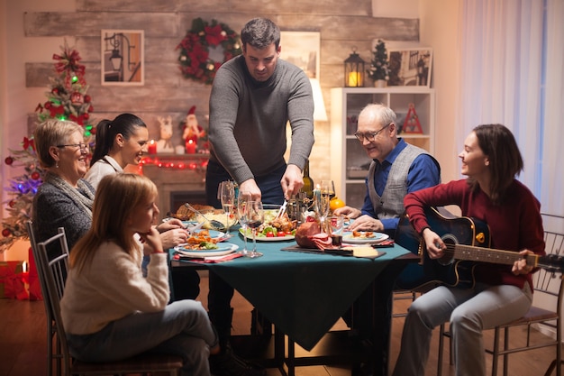 Big family at christmas celebration listening girl singing on guitar.