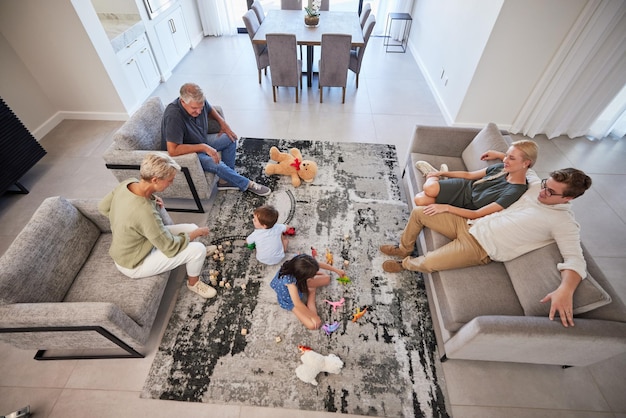 Big family in living room home with parents baby or children play on carpet for growth development and wellness Overhead grandmother and grandfather talking to kids for language learning in lounge