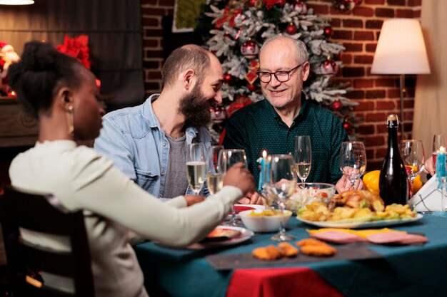 クリスマスイブに大家族が集まり、一緒にお祝いディナーを楽しみ、ワインを飲み、12月のお祝いをします。老若男女が旬の料理とお酒で幸せな食卓を囲みます。