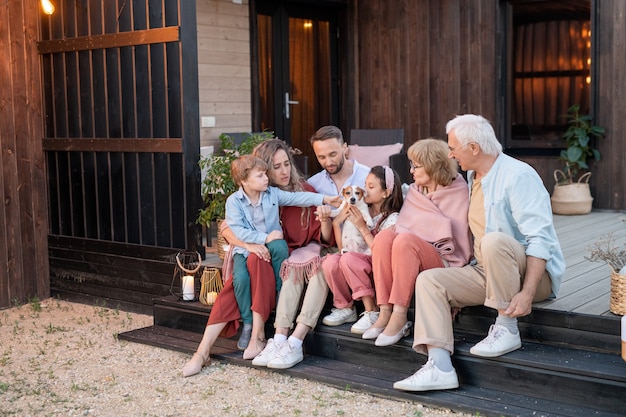 Foto grande famiglia di sei persone e il loro adorabile animale domestico che riposano sul patio