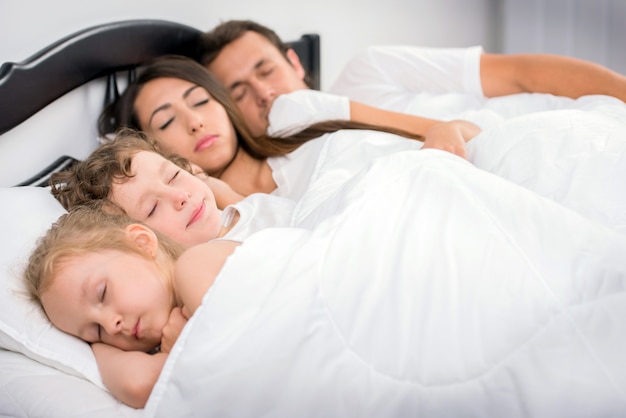 Big family sleeping together in bed.