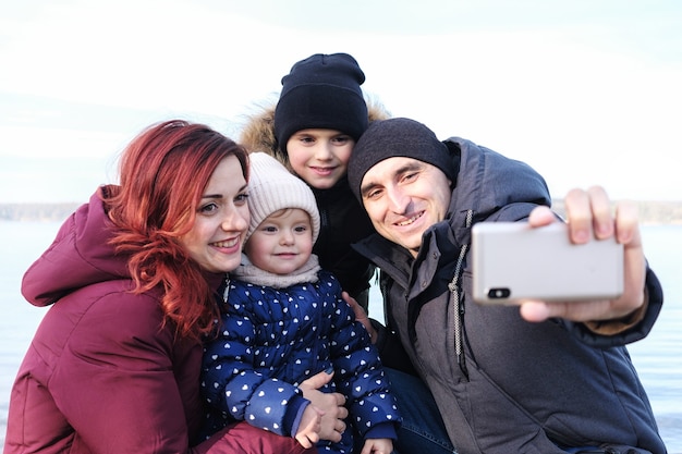큰 가족은 겨울에 해변에서 셀카를 찍습니다-행복한 부모와 아이들이 함께