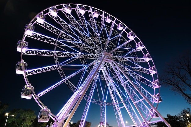 Big ferris wheel at night glowing with lights at night