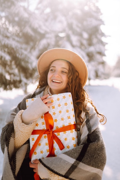 Большая подарочная коробка с красной лентой в руках женщины Модная молодая женщина с рождественским подарком