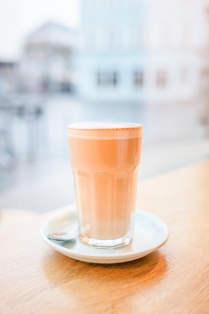 Grande bicchiere con caffè latte vicino alla finestra, morbido e pastello