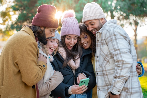 휴대 전화를 찾고 젊은 multiracial 친구의 큰 그룹은 야외에서 웃는 행복 흥분