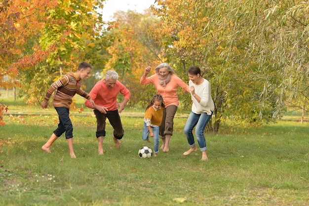 Foto grande famiglia felice che gioca a calcio nel parco