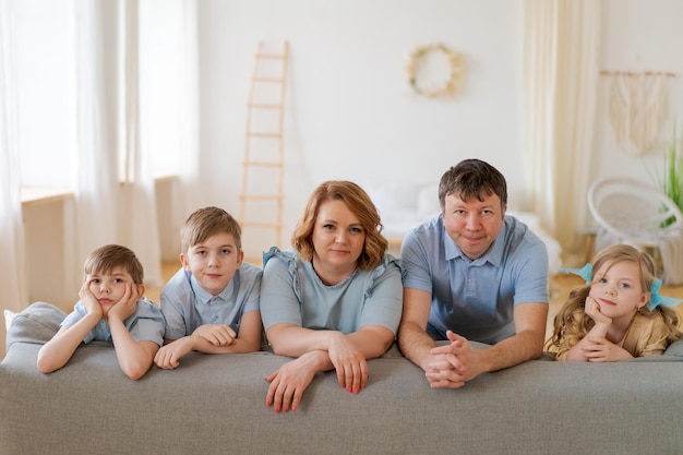Foto grande famiglia felice che posa vicino al nuovo divano acquistato in un salotto luminoso a casa