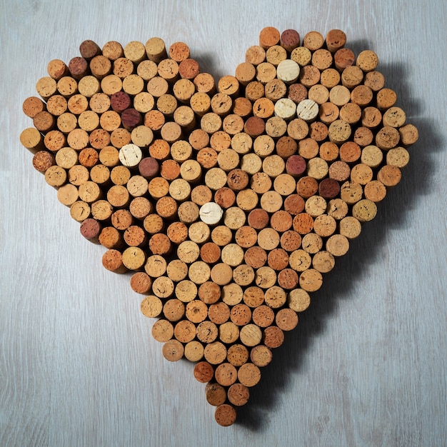 Big heart made of cork wine corks on wooden background, wine design concent