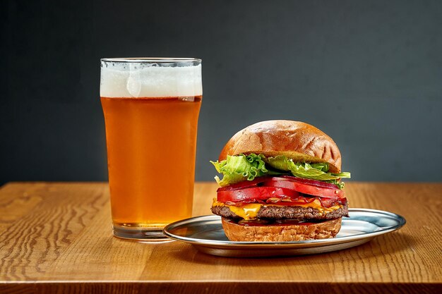 Un grande hamburger succoso con verdure e un bicchiere di birra messa a fuoco selettiva del primo piano