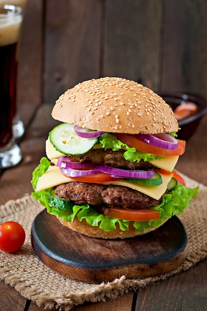 Big juicy hamburger with vegetables and beef on a wooden table in rustic style