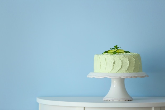 밝은 파란색 벽 옆에 있는 흰색 스탠드에 있는 큰 라임 케이크