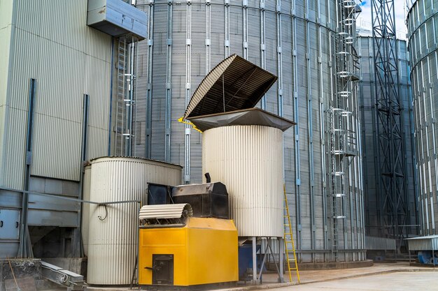 곡물 창고에 있는 큰 금속 탱크 산업용 철강 사일로 근처에 있는 개별 수조 산업 지역의 엘리베이터 근접 촬영