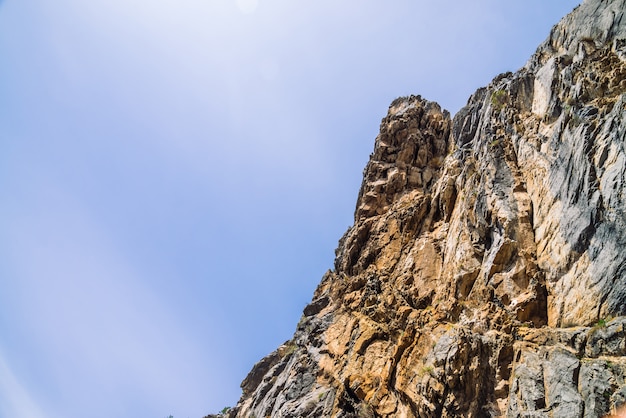 Big mountain cliff under cloudy sky close-up.