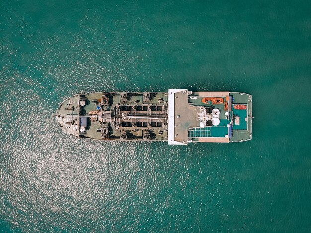 Big oil tanker sailing blue sea to the coastal depot, top view; fuel concept.