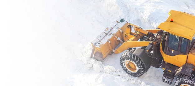 Big orange tractor removes snow from the road and clears the sidewalk