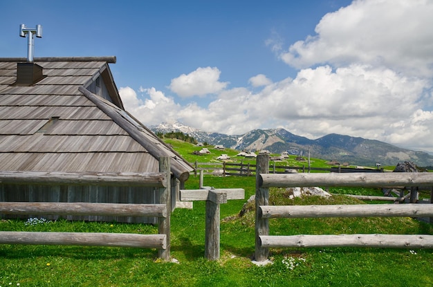 Big Pasture Plateau in Alps, Slovenia. Mountain cottage hut or house on green hill. Alpine landscape