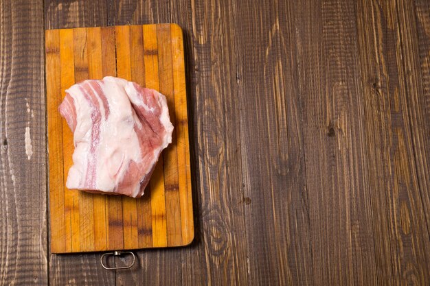 A big piece of pork is on a plank at the table