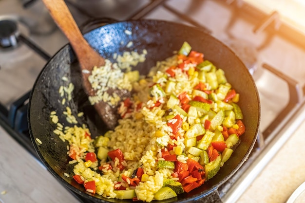 A big pilaf pan bowl with mix of vegetables cooking on the kitchen rice with red beans and