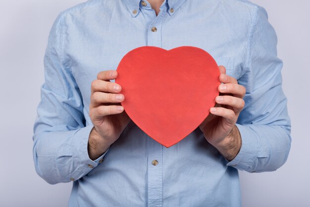 Big red box in shape of heart in male hands. gift for beloved. present for valentine's day